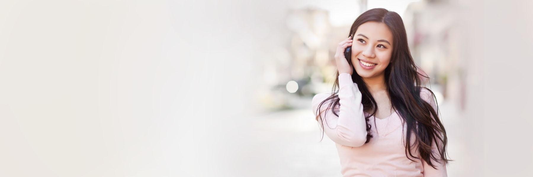 woman with long brown hair smiling and holding her face with one hand