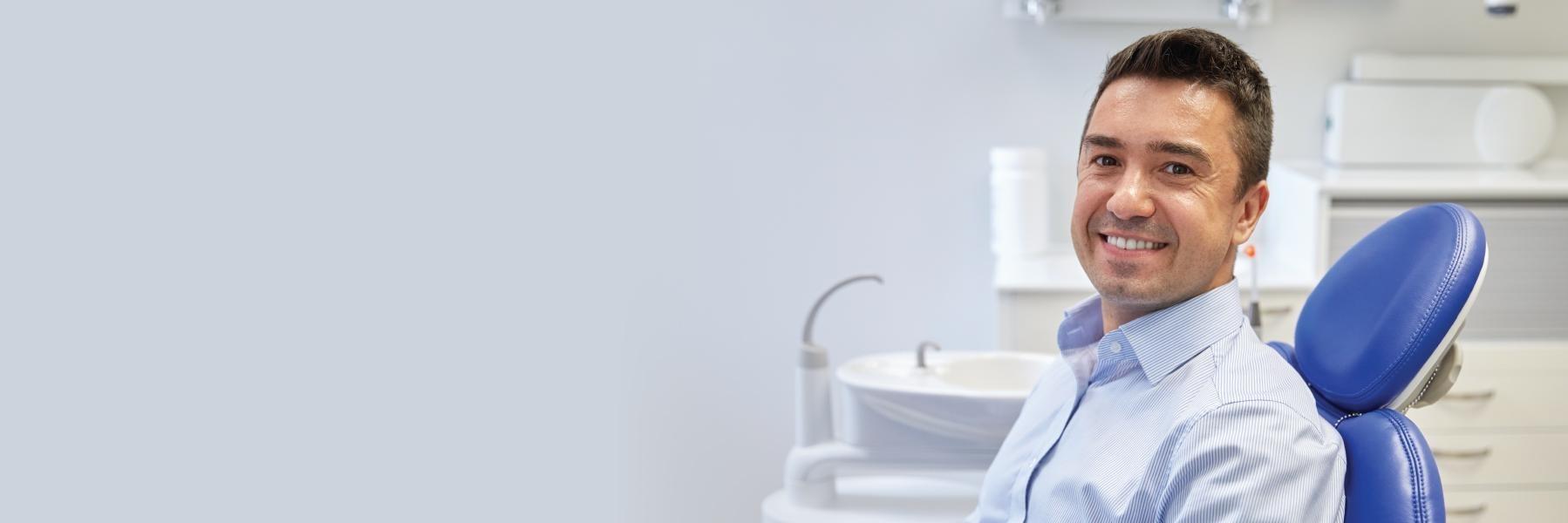 Man smiling sitting in dental exam chair l Sedation dentistry red deer county AB